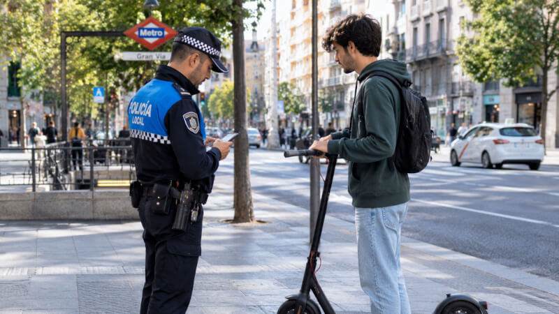 Agente de policia verificando la placa de marcaje DGT y certificado de un patinete electrico